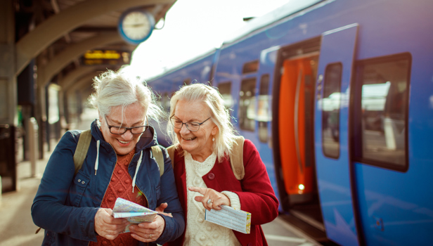Two elderly women standing at a platform. They are looking at a map.